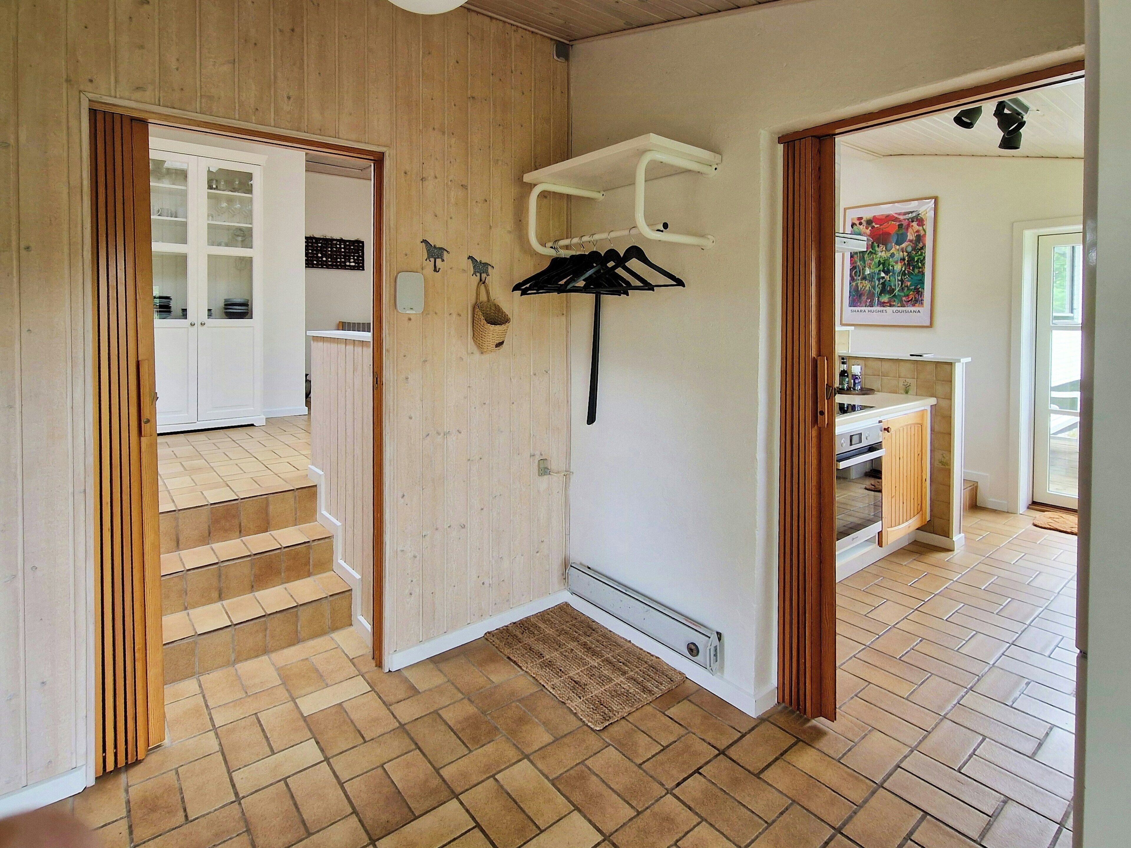 A kitchen with a built-in oven, a hanging rack, and a window with a view of the outdoors.