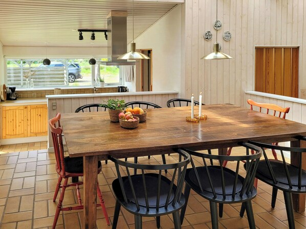 Una mesa de comedor de madera con sillas, un área de cocina con armarios de madera y una ventana con vistas al exterior.