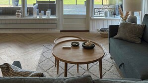 A living room with a view of the sea, a wooden coffee table, a sofa, and a lamp. - Summer house with sea view on Fyn (Asperup)