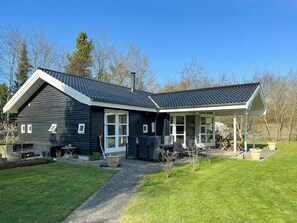 A modern house with a sloped roof, a covered porch, and a well-maintained lawn. - Holiday home with sauna near Anneberg (Højby)