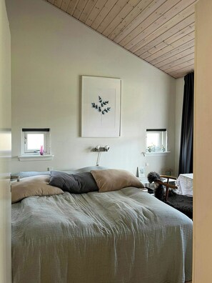 A bedroom with a bed, a window with a view, a wall-mounted picture, and a bedside table. - Holiday home with sauna near Anneberg (Højby)