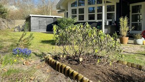 Una casa con un amplio ventanal delantero, patio trasero cercado y un cobertizo pequeño.
