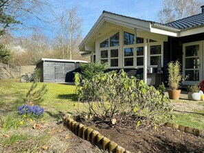 A house with a large windowed front, a fenced backyard, and a small shed. - Holiday home with sauna near Anneberg (Højby)