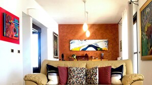 Ein Wohnzimmer mit einem beigen Sofa, einem Glastisch und einem Gemälde an der Wand.