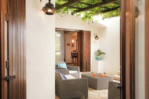 Eine offene Terrasse mit Korbmöbeln, einer Holztür und einer hängenden Lampe.