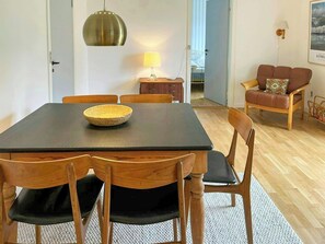 A dining area with a table, chairs, a lamp, and a sofa. - Retro holiday home by Thy National Park (Bedsted)