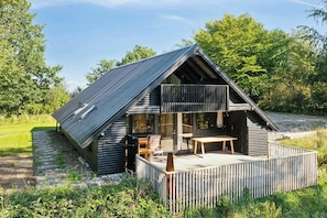 Eine Holzhütte mit Balkon, Terrasse und Essbereich.