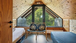 A room with a sloped ceiling, a bed, a chair, and a window overlooking a balcony. - 70s holiday home with fjord views at Lyby Beach (Roslev)