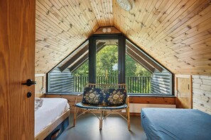 A room with a sloped ceiling, a bed, a chair, and a window overlooking a balcony. - 70s holiday home with fjord views at Lyby Beach (Roslev)
