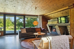 Ein gemütliches Wohnzimmer mit Kamin, einer Couch, einem Couchtisch und einem Fernseher.