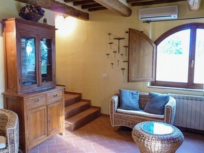 A room with a wooden cabinet, wicker furniture, a window with a view, and a staircase. - Private pool stone villa overlooking Crete Senesi (Asciano)