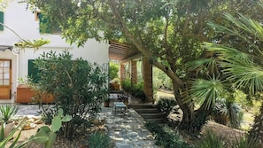 A garden with a stone pathway leading to a wooden bench and a table, surrounded by various plants and trees. - Villa with 360° panoramic sea views and a jacuzzi (Caccamo)