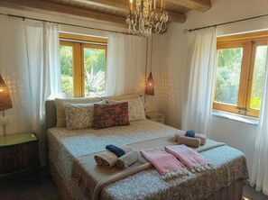 A bedroom with a bed, two bedside tables, a chandelier, and windows with curtains. - Villa with 360° panoramic sea views and a jacuzzi (Caccamo)