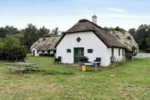 A white building with a thatched roof, a green door, and a small window. - Renovated stable with seaweed roof on Læsø (Læsø)