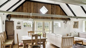 Un intérieur rustique avec une table à manger en bois, des chaises, un canapé et une grande fenêtre.