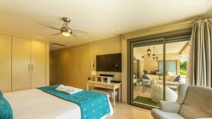 Hotelkamer met een bed, bureau, stoel, televisie en een glazen schuifpui naar een balkon.