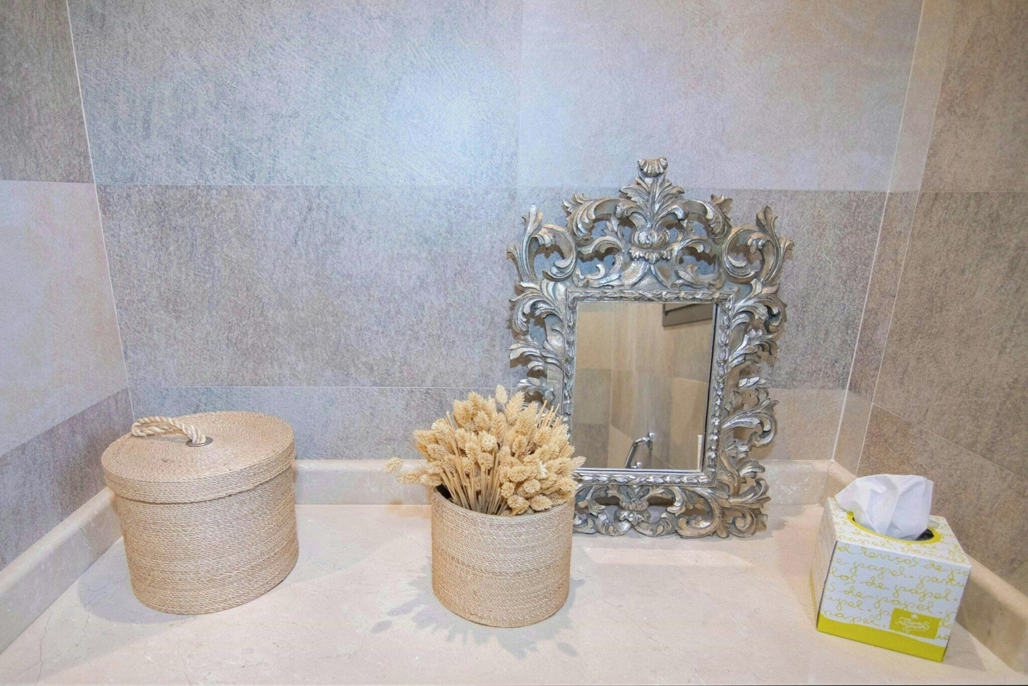 A bathroom with a mirror, a trash bin, and a tissue box.