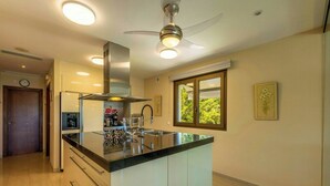 Een moderne keuken met een centraal eiland, inbouwapparatuur en een plafondventilator.