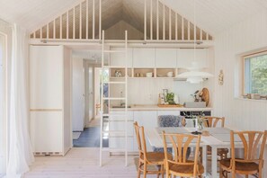 Eine moderne Küche mit weißen Schränken, ein Essbereich mit Holzkohlenstühlen und eine sichtbare Treppe, die in einen anderen Raum führt.