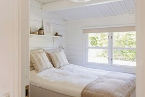 Ein Schlafzimmer mit Bett, Fenster und einer Ablage mit Dekoration.