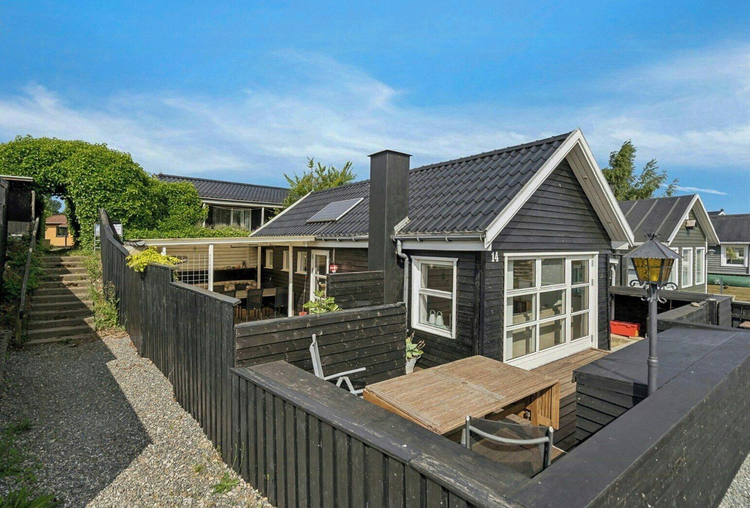 Une rangée de cabanes dotées d’une terrasse en bois, d’un espace extérieur couvert avec des sièges et d’une cheminée.