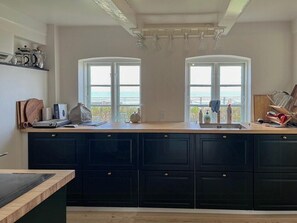 Eine Küche mit dunklen Schränken, einer Holz Arbeitsplatte und zwei Fenstern mit Blick.