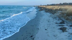 Ein Strand mit Wellen, Seetang und Fußspuren.