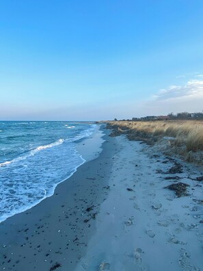 Ein Strand mit Wellen, Seetang und Fußspuren.