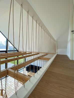Ein modernes Interieur mit Holzboden, weißer Decke und Blick durch große Fenster.