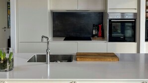 A modern kitchen with a stainless steel sink, a built-in oven, and pendant lights. - Modern house with sea view near Faaborg (Faaborg)