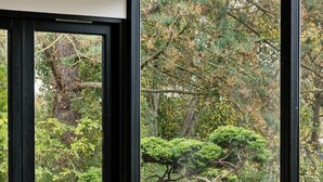 A room with a large window, a wooden table, and two chairs with striped cushions. - 70s holiday home with views of Vesterlyng (Føllenslev)