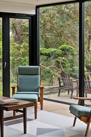 Ein Zimmer mit einem großen Fenster, einem Holztisch und zwei Stühlen mit gestreiften Kissen.