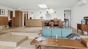A modern living space with a sofa, dining table, and kitchen area. - 70s holiday home with views of Vesterlyng (Føllenslev)