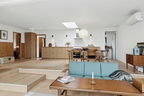 Ein modernes Wohnzimmer mit Sofa, Esstisch und Küchenzeile.