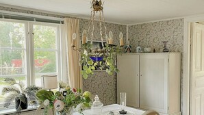 Comedor con mesa dispuesta para dos, una araña y vista al exterior.