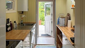 Una cocina estrecha con encimera de madera, una ventana y una puerta que da al exterior.
