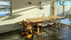 A dining area with a wooden table and chairs, pendant lights, and a view of a snowy landscape through a window. - Architect-designed cottage by the water (Middelfart)