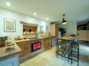 Eine moderne Küche mit Holzausstattung, einem Backofen, einer Spüle und einer Bar mit Hockern.