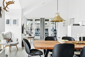 Ein moderner Essbereich mit Holztisch, schwarzen Stühlen und einer großen Pendelleuchte.