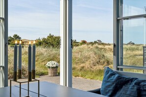 Ein Zimmer mit einem großen Fenster, einem Tisch mit Kerzen und Blick ins Freie.