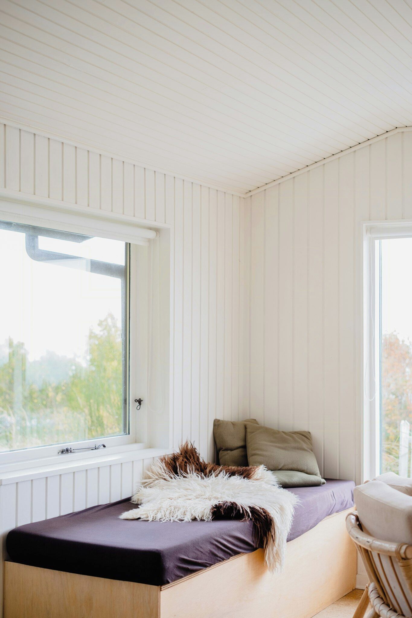 Ein Schlafzimmer mit Bett, Fenster und einem Sessel.