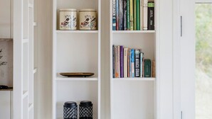 Een witte kamer met ingebouwde planken vol boeken en decoratieve objecten.