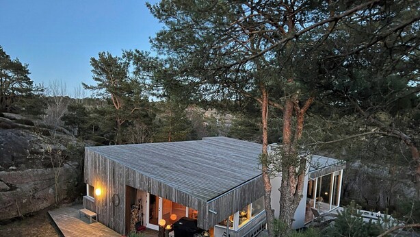 Eine Holzhütte mit einer Terrasse und einer überdachten Veranda.