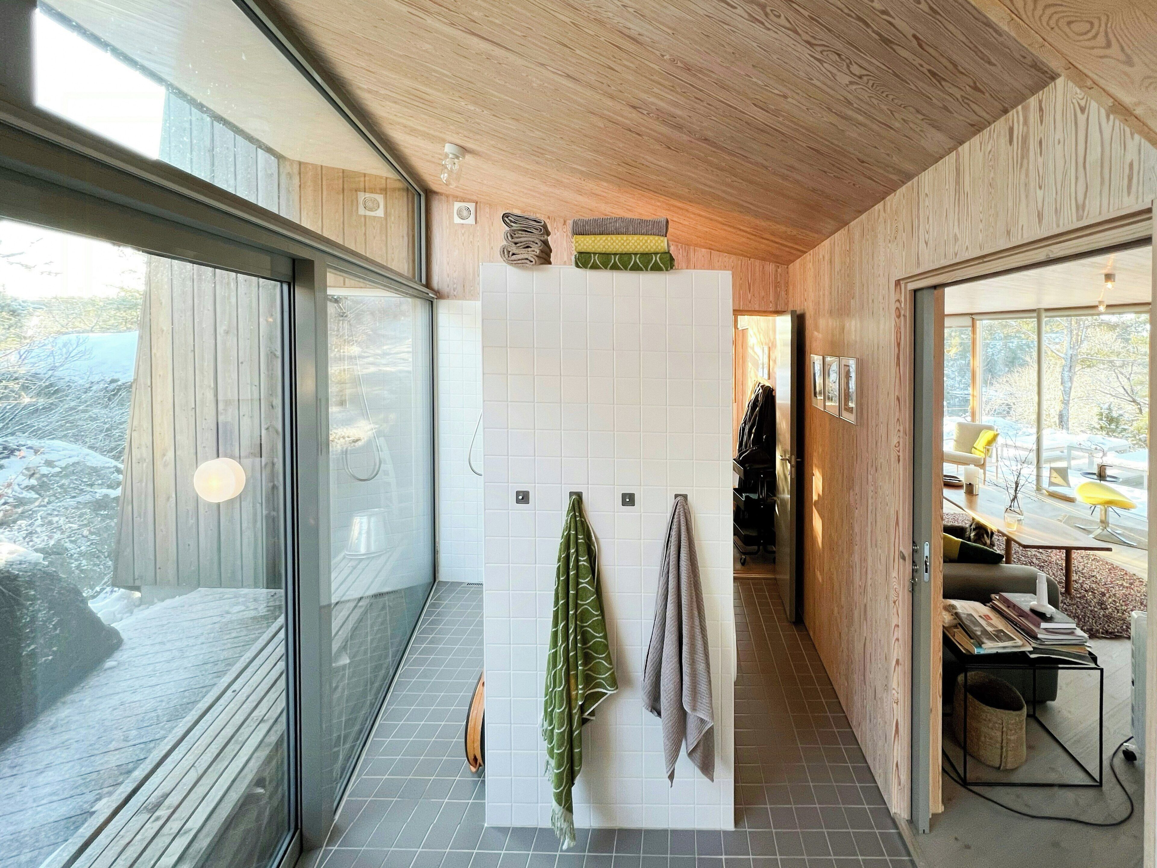 Un interior moderno con techo de madera, puerta de cristal que da al exterior y vista a un paisaje nevado.