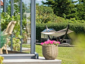 A hammock chair in a garden with a metal structure and a potted plant.