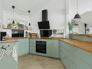 A modern kitchen with a built-in oven, a black range hood, and a wooden countertop. - House with ferry views by Isefjorden (Holbæk)