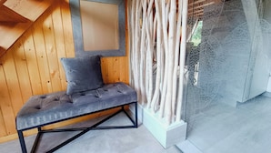 Een hoek van een kamer met een met kussens beklede bank, een lijst met foto en een decoratieve houten constructie.