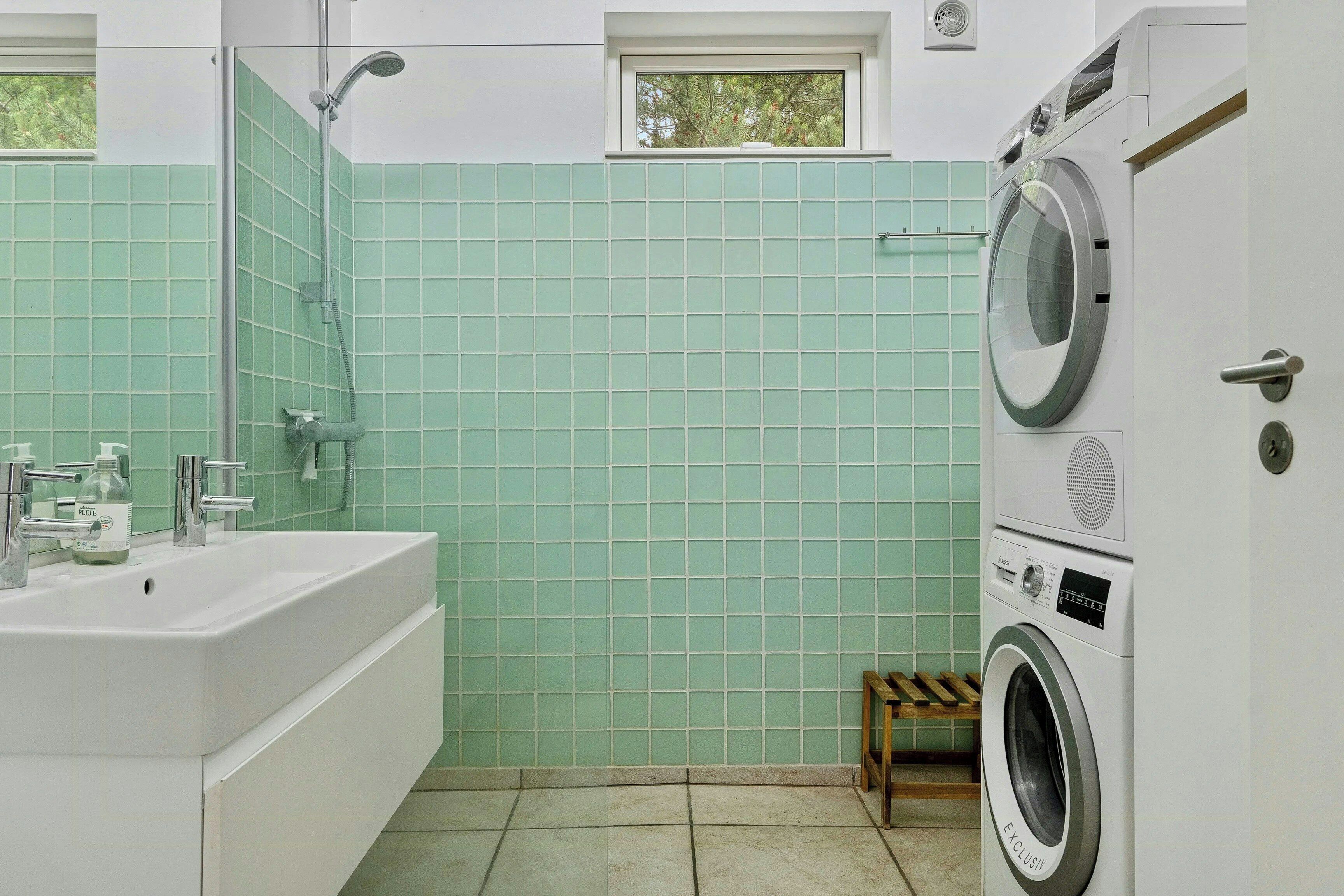 Une salle de bain équipée d’un lavabo, d’une douche et d’un lave-linge.