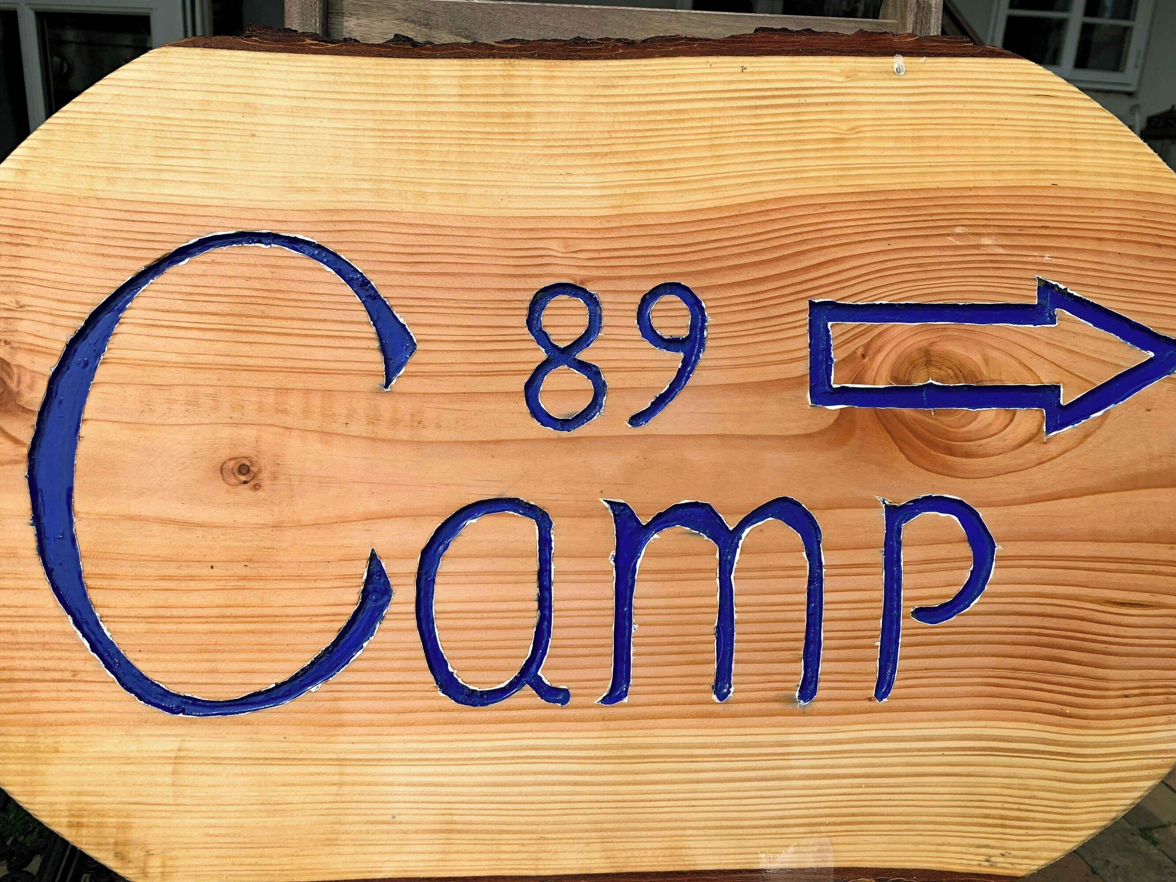 Ein hölzernes Schild mit der Nummer 89 und einem nach rechts zeigenden Pfeil, der den Weg zum Camp weist.