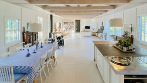 Une cuisine spacieuse avec un long comptoir, des armoires blanches et un plafond en bois.